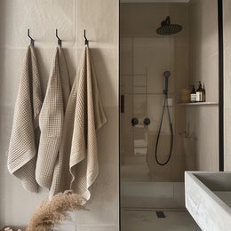 Waffle-textured bath towel in stone green, pure white, sand brown, almond brown, and storm blue colors. Soft, absorbent, and durable material.