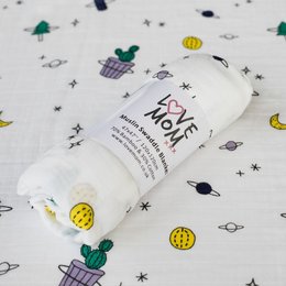 A soft, cozy swaddle blanket featuring a space-themed pattern with planets, stars, and other celestial elements in various colors.