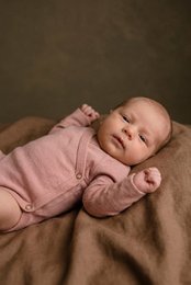 A long sleeve, wrap-style baby romper made of soft, cozy merino wool in a misty rose color. Features a wrap-around design with snap closures for easy dressing.