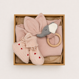 Soft pink knitted baby booties with red hearts, bunny ears toy, wooden ring, gift box set for newborns.