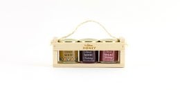 Wooden gift box with 3 jars of blossom honey, honey with blueberries, and honey with cranberries. The box is made of natural wood and has a hanging rope handle.