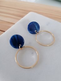 Blue statement earrings with gold-tone circular hoops and blue resin discs.