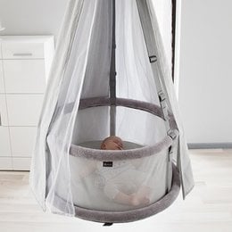 A premium 3-in-1 crib with a round, elevated design, featuring a white and gray color scheme and a mesh canopy.