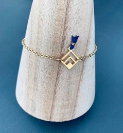 A delicate gold-toned charm bracelet with a geometric charm and red and blue accents, perfect for adding a touch of style to any outfit.