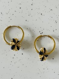 Gold hoop earrings with black flower accents.