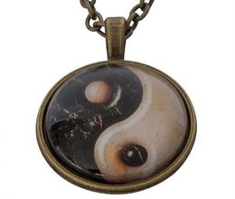 A round pendant featuring a yin-yang symbol with a black and white design and two small spheres.
