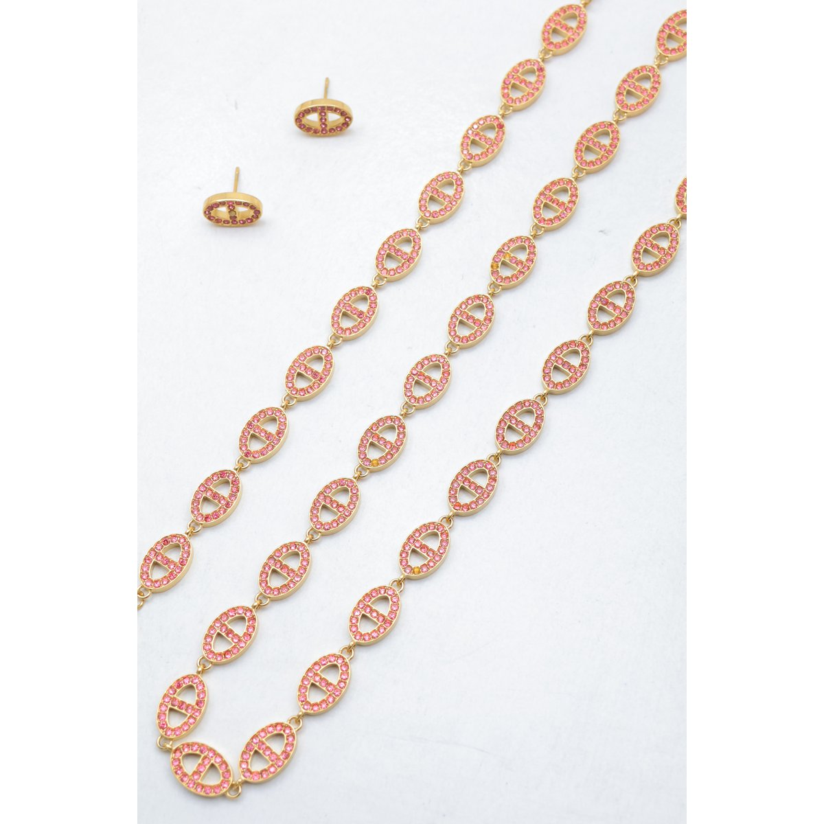 Ensemble assorti comprenant un collier, un bracelet en chaîne et une paire de boucles d'oreilles puces. Chaque bijou est composé d'une succession de maillons en forme de maille marine entièrement pavés de petits strass scintillants.