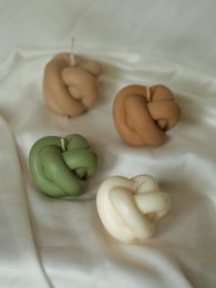 Knot-shaped white wax candle with a natural, organic appearance.
