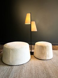Plush, round ottomans in a neutral color palette with modern table lamps. Ideal for cozy living spaces.