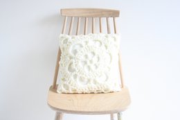 Ecru crocheted cushion with intricate floral pattern, made of soft, textured material, suitable for home decor.