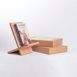 A bamboo book stand with a pink book titled "Graphic Anatomy 2 Atelier Bow-Wow" displayed on it. The book stand is made of natural bamboo material and has a simple, minimalist design.