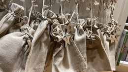 A numbered advent calendar with a "Stars" theme, featuring small fabric pouches hanging from a wooden frame with silhouettes of trees.