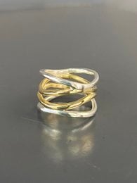 A statement ring featuring a wave-like design in a combination of silver and brass metals.