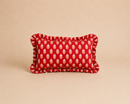 Rectangular cushion with a sunset motif and polka dot pattern in shades of red.