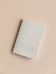 A minimalist bullet journal notebook with a soft gray cover and subtle text detailing.