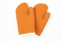Orange waffle cloth oven mitts with textured surface for heat protection.
