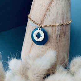 Charm bracelet with a round pendant featuring a star design in blue and white enamel. The bracelet has a delicate gold-tone chain.