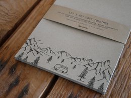Camper con blocco note in carta erba in montagna