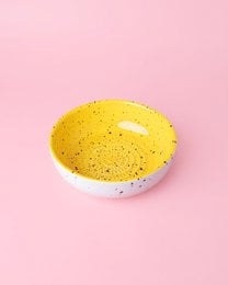 Ceramic cheese grater in a vibrant yellow color with a speckled pattern, suitable for grating cinnamon or other spices.