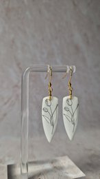  White dagger-shaped earrings with delicate line art design.