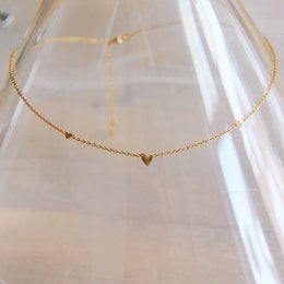 A delicate gold necklace with three mini heart charms, perfect for adding a touch of elegance to any outfit.