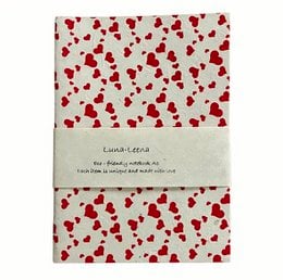 A5 notebook with a soft cover, eco-friendly paper, and a heart print pattern in red on a light background. The notebook is handmade in Nepal.