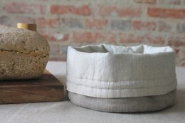 Linen bread basket with a round, woven shape and neutral color palette. Suitable for storing and serving bread.