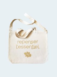 Beige canvas tote bag with gold text "repenser l'essentiel" and a gold paw print design. The bag has a simple, minimalist style and appears to be made of durable, high-quality materials.