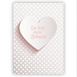 A romantic greeting card with a heart-shaped design and the text "Du bist mein Zuhause" (You are my home) in pink lettering. The card is set against a white background with a subtle polka dot pattern.