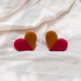  Studs heart-shaped earrings in magenta and ocher yellow colors.