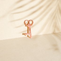Copper-colored hand sanitizer bottle with a key-shaped cap. The bottle has a minimalist, modern design.