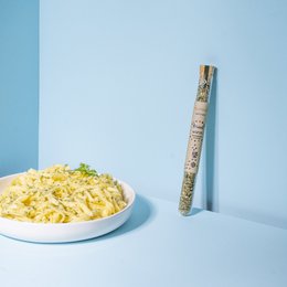 A blend of aromatic spices in a white container, featuring a mix of dried herbs and seasonings.