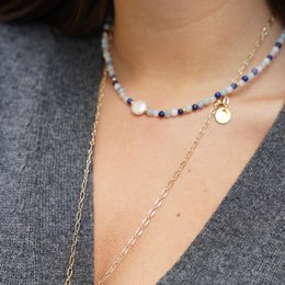 Delicate blue and white beaded charm necklace with a pendant.