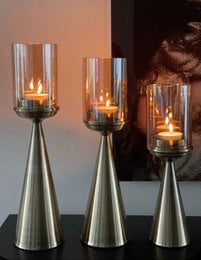 Tall, gold-colored glass candle holders with cylindrical glass inserts for tea lights.
