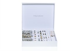 Rectangular white display box with various jewelry items inside, including necklaces, earrings, and bracelets. The box is labeled "Star of Sweden" and the interior has a patterned lining.