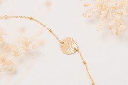 Delicate gold-toned charm bracelet with intricate leaf-shaped charm.