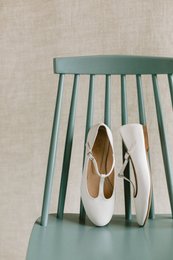  White leather ballerina flats with a round toe shape and a low heel. The flats have a simple, minimalist design and are suitable for casual or formal wear.