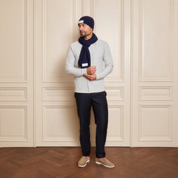 Navy blue knitted beanie with a white label patch, suitable for cold weather wear.