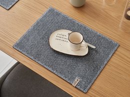 Square grey felt placemat with a simple, minimalist design suitable for a modern dining table.