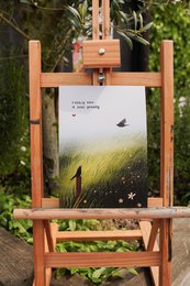 # Product Description
Minimalist nature illustration print with bird, golden wheat field, serene landscape art on wooden easel display.