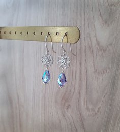 Silver flower earrings with tanzanite AB crystal drops. Elegant drop earrings featuring a silver flower design with sparkling tanzanite AB crystal accents.