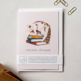 Greeting card with a cat sitting on a stack of books, with the text "Cats, books... Life is good!" The card features a whimsical illustration of a cat surrounded by books, suggesting a love for reading and cats.