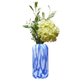 Decorative blue and white swirled glass vase holding a bouquet of yellow flowers.