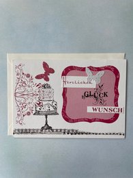 Folding greeting card with envelope featuring a decorative frame, butterfly, and the German text "Herzlichen Glückwunsch" (Congratulations).