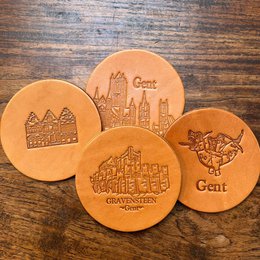 Leather coasters featuring the Ghent skyline and other Ghent-themed designs. Available in variants like Ghent dragon, Gravenstone, Belgian Beer, and Comboset (4p).
The product images show a set of round leather coasters with various Ghent-themed designs engraved on them, including the Ghent skyline, a dragon, and other architectural elements. The coasters appear to be made of high-quality leather and would be suitable for use in homes or offices to protect surfaces from drink stains and scratches.