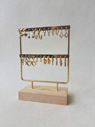 # Product Description

Gold metal jewelry display stand with two tiers, wooden base, hanging chains and hooks for necklaces and bracelets.