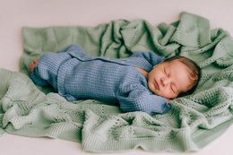 Soft, cozy mint green plaid baby blanket. Newborn baby sleeping peacefully wrapped in the warm, textured blanket.
