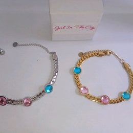 Stainless steel chain bracelet with faceted crystals in blue, pink, and gold tones. Elegant gourmette style.