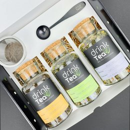 Organic tea gift set containing three glass jars with green tea, black tea, and herbal tea blends. The jars feature a simple, minimalist design with the "Drink Tea" branding.