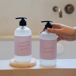  A gift set containing a handwash and bodywash with the text "hey gorgeous" printed on the bottles. The bottles have a minimalist, pastel-colored design.